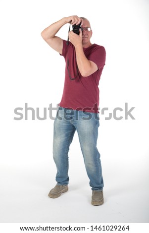 Mature casually dressed male taking photographs with a digital camera. In studio on white background
 hobby or pastime