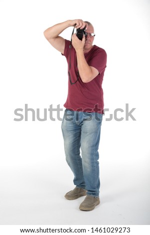 Mature casually dressed male taking photographs with a digital camera. In studio on white background
 hobby or pastime