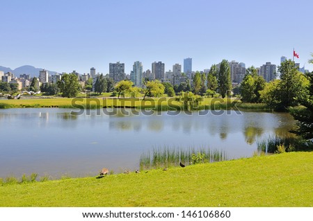 A lake in a park with city skyline in the background