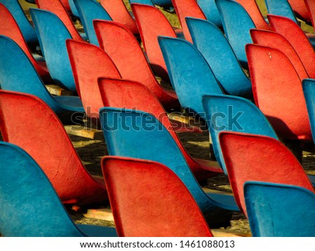 Red chairs and blue chairs in an outdoor auditorium.