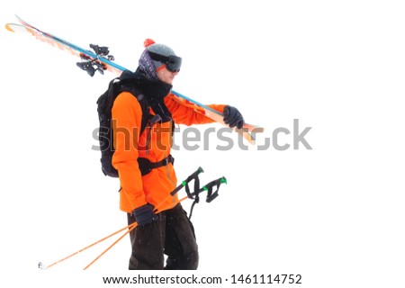 Portrait of a professional athlete skier in an orange jacket wearing a black mask and with skis on his shoulder looks into the camera. Isolated on white