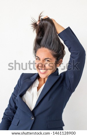 Excited businesswoman holding hair. Emotional young woman in formal wear having fun and laughing at camera isolated on grey background. Emotion concept