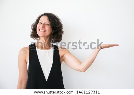 Joyful excited woman in casual presenting information. Middle aged business lady standing over white studio background and showing copy space with hand. Presenting concept