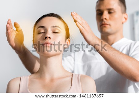 woman sitting with closed eyes while healer cleaning her aura Royalty-Free Stock Photo #1461137657