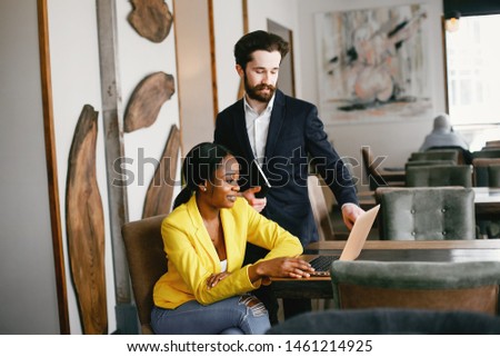 Handsome man in a black suit. Woman in a yellow jacket. Businessman working in a office