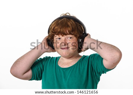 Freckled red-hair boy listening music. Isolated on white background.