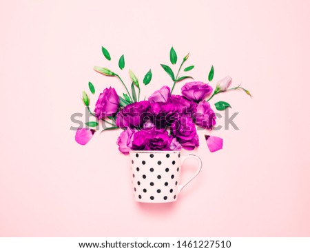 Cup of coffee abd beautiful flowers on pink background. Bright flower composition. Top view, flat lay. Lisianthus or eustoma.