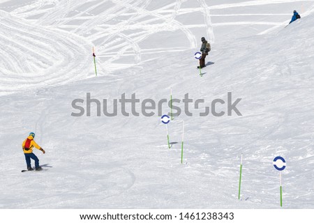 Skiers and snowboarders downhill on snowy ski trace at sunny cold day. Caucasus Mountains in winter, Georgia, region Gudauri, mount Kudebi.