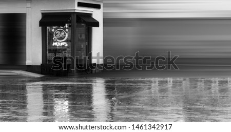 Open 24 Hours neon sign on a restaurant window with italian awnings. Summer rainy evening. Streetfood concept. Copyspace for cafe name. Black and white photo