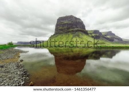 Great Northern Pristine Nature of Iceland, beautiful natural landscape. Sophisticated Greenish mountain covered with moss, reflected in small lake. Overcast weather, Summer  time. 