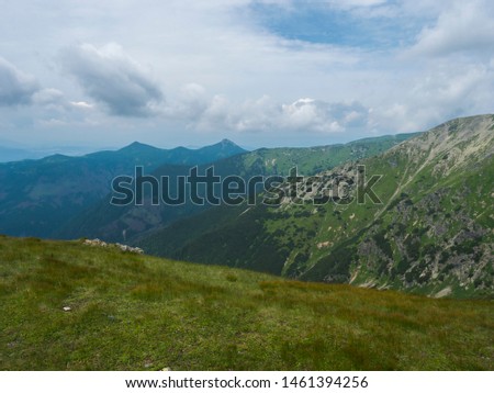 Beautiful mountain landscape with lush green grass, meadow and bare mountain peaks on ridge Western Tatras mountains, Rohace Slovakia, summer dramatic clouds sky background