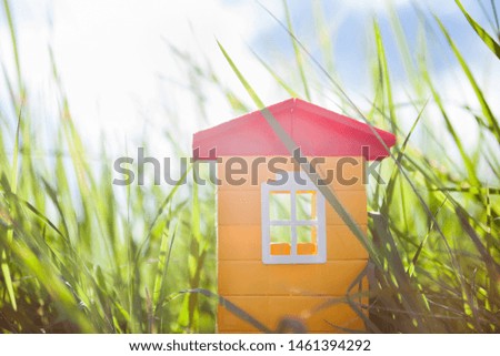 Plastic toy house in the green grass in the sunshine. Home and happiness, childhood and dreams concept.