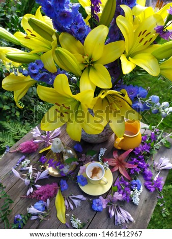 A bouquet of luxurious yellow lilies and a Cup of coffee on the table in the garden of the cottage