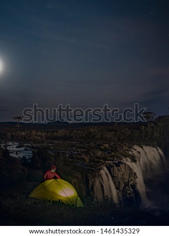 Man camping near a waterfall at night under the stars. Long exposure photography. Caveiras, Santa Catarina, Brazil. Adventure camping and trip. Green tent of a nomad.