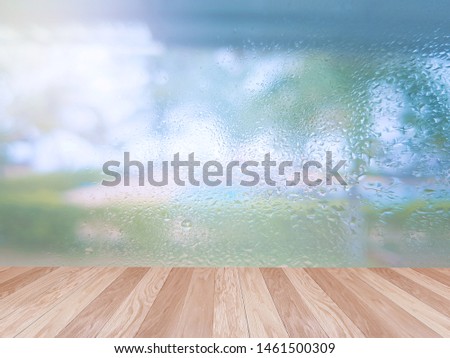 Empty wooden table for displaying products. 
On a rainy day, seeing a drop of water on the outer glass blurred (Background, rainy day window)
