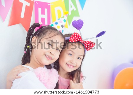 Colorful portrait of two happy asian girls sitting together in celebration of birthday and smiling.