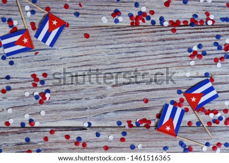 October 10, happy independence Day of Cuba. the concept of patriotism , freedom and independence. Mini flags with paper confetti on wooden background, horizontal