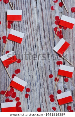 November 11, independence Day of Poland, the concept of independence , patriotism and freedom. Mini paper flags with white red confetti on wooden background. vertical