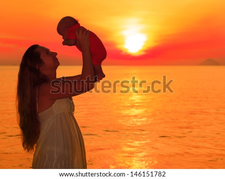 Mother and baby on the beach at sunrise