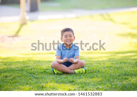 A boy smiling on green grass at park