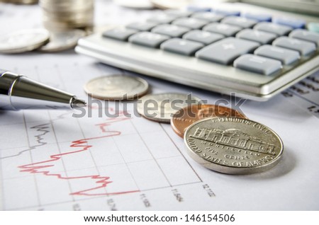 Stock graph with calculator, pen and coins