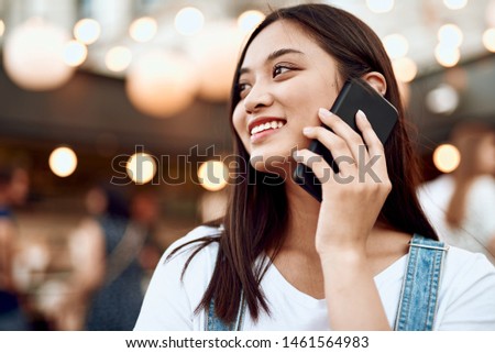 Walking around concept. Portrait of young pretty smiling asian woman talking by mobile phone