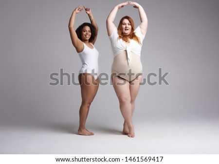 Obese Caucasian woman and Afro American lady imitating ballet dancers