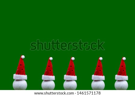 Golf ball wears Santa hat isolated on green background