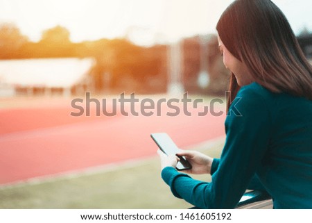 concept of contact business,people communication,technology electronic device. woman or student hand holding, using and touch screen mobile smartphone At the stadium of the international university