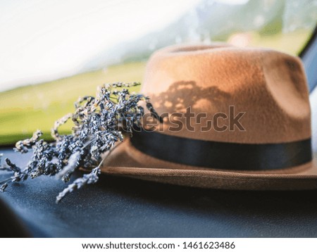 Still life - a bouquet of lavender lies near a wide-brimmed hat on the front window of the car