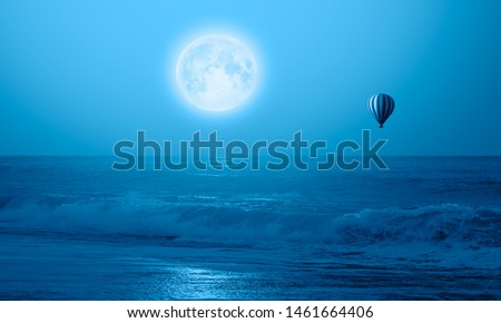 Night sky with full moon over the storm sea with hot air balloon "Elements of this image furnished by NASA