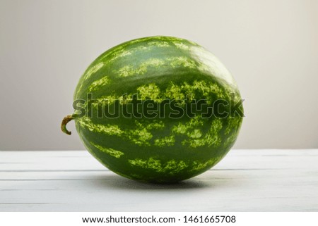 ripe whole tasty watermelon on white wooden table isolated on grey