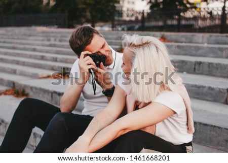 Young happy couple in love shoots each other on retro camera on the city street