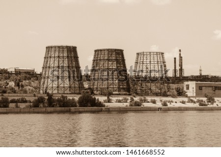 View to the old cooling tower of the old plant or factory on the riverbank of Volga river in Volgograd in the hot sunny clear summer day. Stylized for old photo