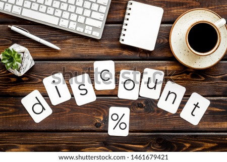 Sale in shop office with discount word and percent symbol, keyboard, notebook on wooden background top view