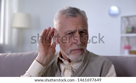 Confused pensioner trying to hear conversation, problem of deafness in old age Royalty-Free Stock Photo #1461697649