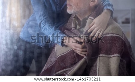 Young woman covering grandfather blanket, family care, nursing home volunteer