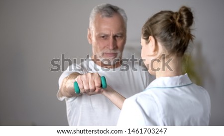 Nurse helping old man to lift dumbbell, cardiac rehabilitation, injury recovery Royalty-Free Stock Photo #1461703247
