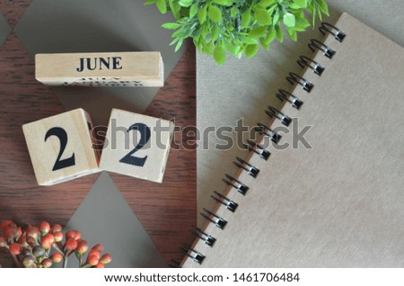 June 22. Date of June month. Number Cube with a flower and notebook on Diamond wood table for the background.