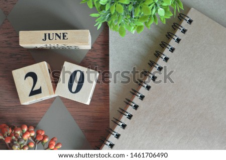 June 20. Date of June month. Number Cube with a flower and notebook on Diamond wood table for the background.