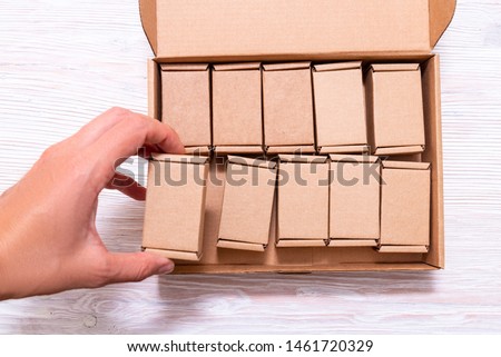 Woman hand putting lot of small cardboard boxes inside of large 