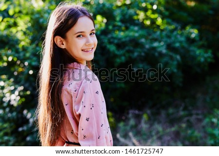     Young smilling black hair girl in the park wearing pink dress against green blurred background