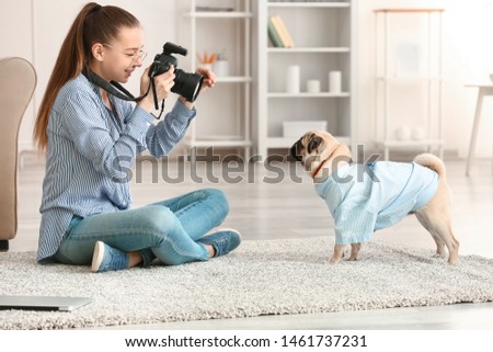 Teenage girl taking photo of her cute dog at home
