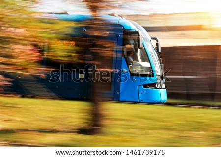 Blue tram running at sunset in  the big city