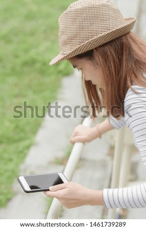 Beautiful girl with straw hat useing phone in the park.