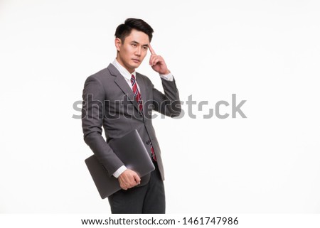 Handsome Asian businessman standing point his finger at his head and holding notebook computer in his hand copy space on right side, isolated on white background.