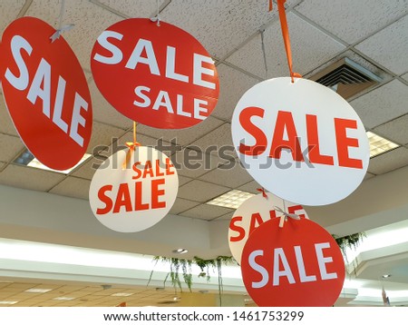 Business "SALE" signs and banner hang on ceiling of shopping mall.