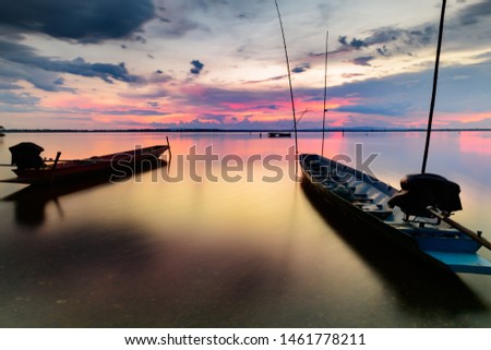Beautiful sky clouds with silhouette of fishing boat at sunset time over lake.