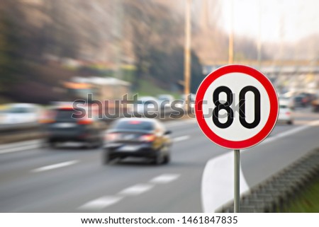 Traffic sign showing 80 km/h speed limit on a highway full of cars