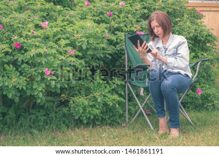 Young attentive red-haired woman on vacation with portable tablet. Enjoying weekend vacation. Woman browses social networks and search engines. Looks at the result. Use tablet concept.